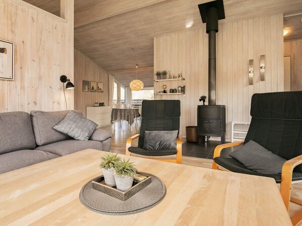 A cozy living room with a sofa, chairs, a coffee table with plants, and a fireplace.