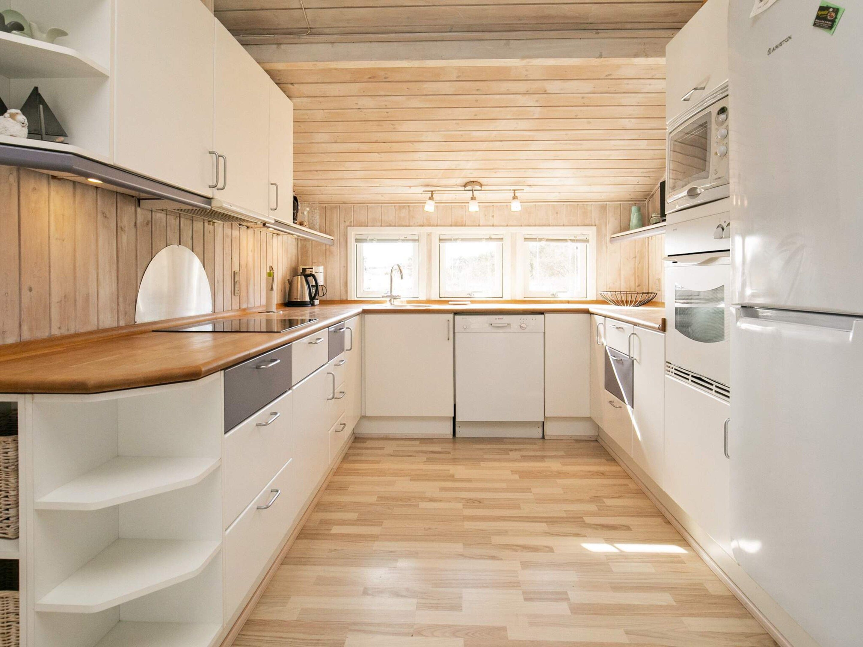 A kitchen with wooden flooring, white cabinets, a built-in oven, and a microwave.