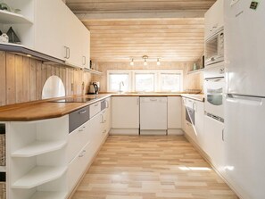 A kitchen with wooden flooring, white cabinets, a built-in oven, and a microwave.