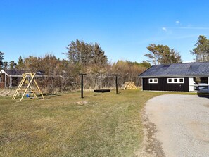 A rural property with a wooden swing set, a small shed, and a gravel driveway.