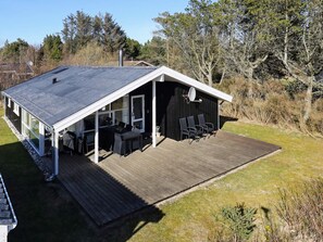 A cabin with a covered patio, a dining area, and a separate seating area with chairs.