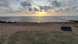A beach with a wooden pier extending into the water, a sandy shore, and a cloudy sky.