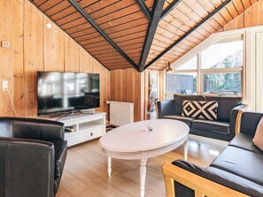 A cozy living room with a wooden ceiling, a flat-screen TV, a white coffee table, and a sofa with patterned cushions. - Alluring Holiday Home in Falster near Sea (Vaeggerlose)