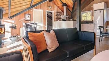 A cozy living area with a sofa, a fireplace, and a kitchen in the background.