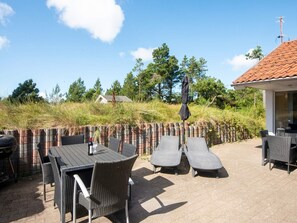 An outdoor patio with a table and chairs, a grill, and a covered umbrella.