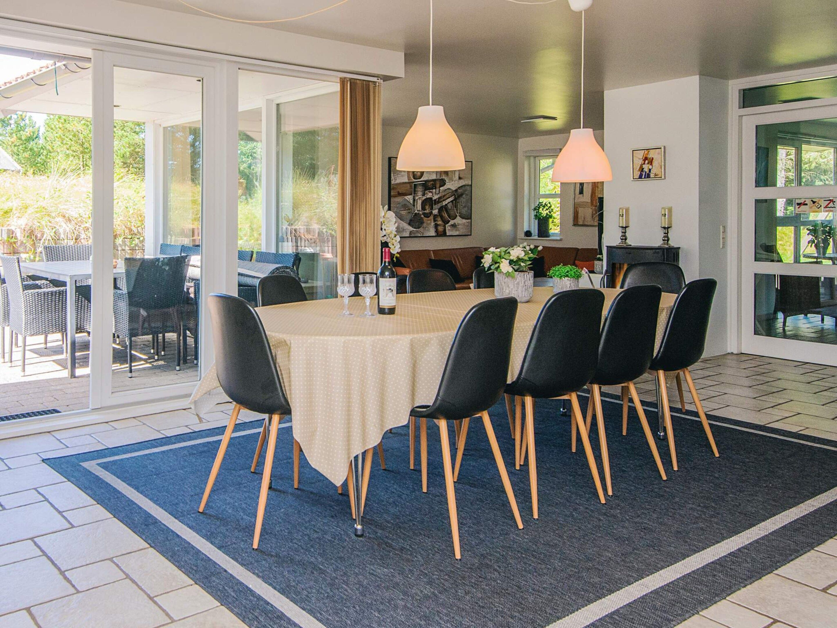 Un coin repas avec une table ronde, des chaises noires et une nappe beige.
