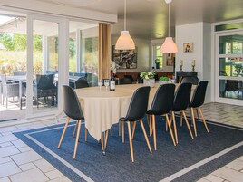 A dining area with a round table, black chairs, and a beige tablecloth.