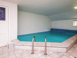 Una piscina con solárium de baldosas y barandillas metálicas.