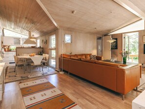 A modern interior with a wooden ceiling, a sofa, a dining table, and a kitchen area.