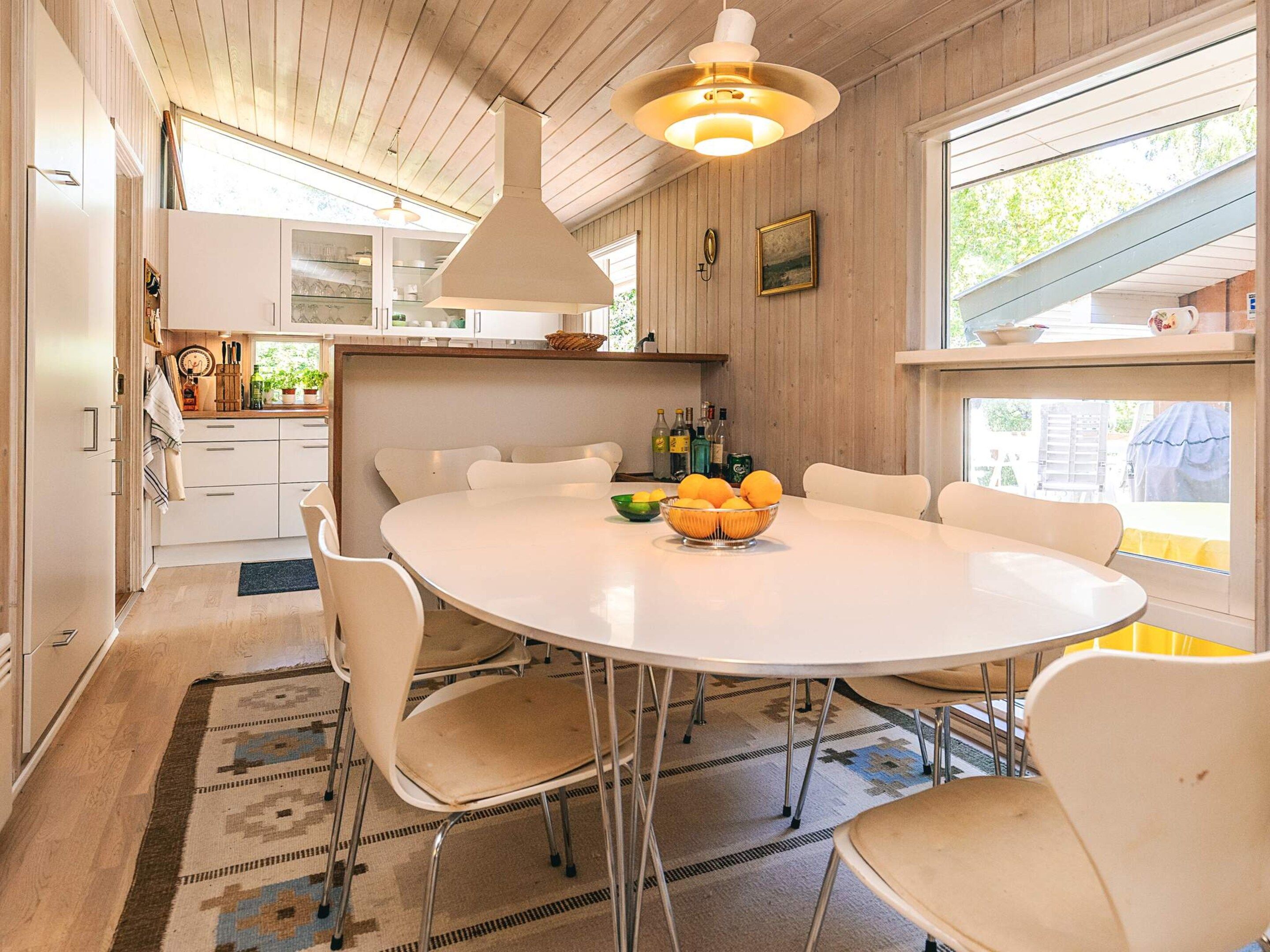 A modern kitchen with white cabinets, a round dining table, and a large window.