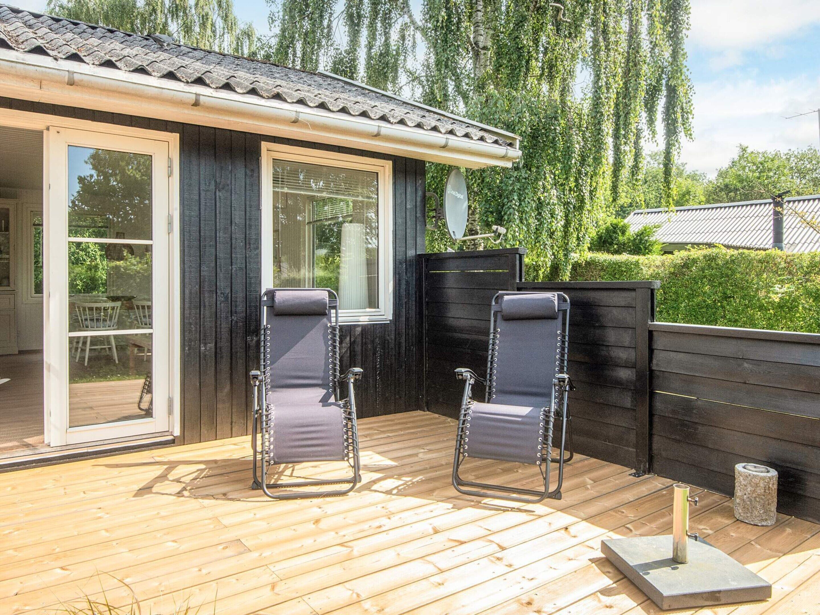 A wooden deck with two reclining chairs and a stone lantern.