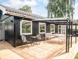 Una terraza de madera con mobiliario exterior y una zona cubierta.