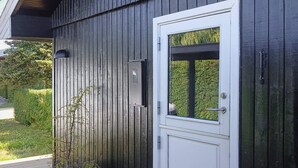 A wooden deck with a white door and a small window. - 4 Person Holiday Home in Juelsminde (Horsens)