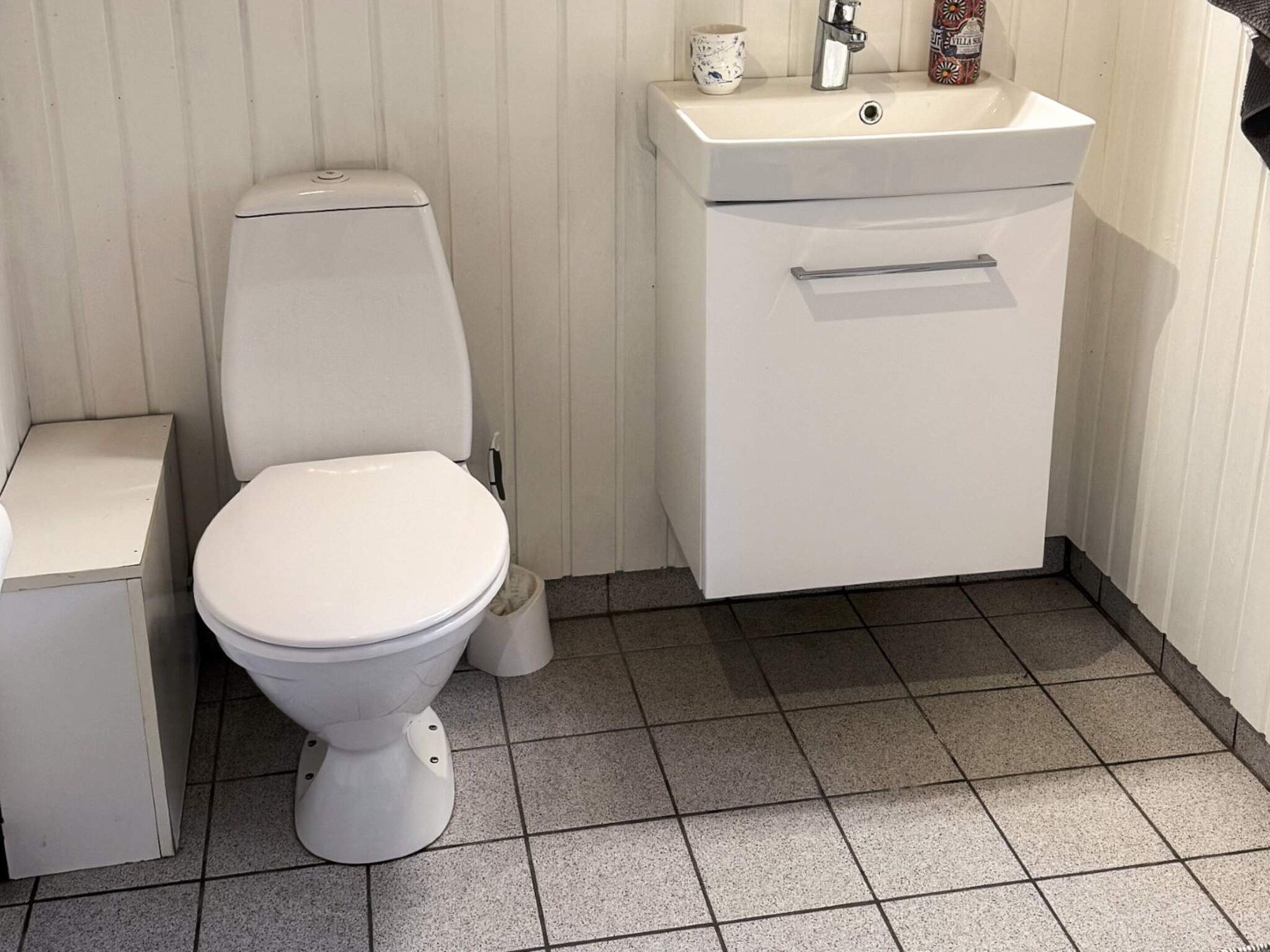 A bathroom with a toilet, a sink, and a small trash bin.