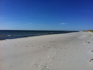 A beach with a clear sky, sandy shore, and gentle waves.