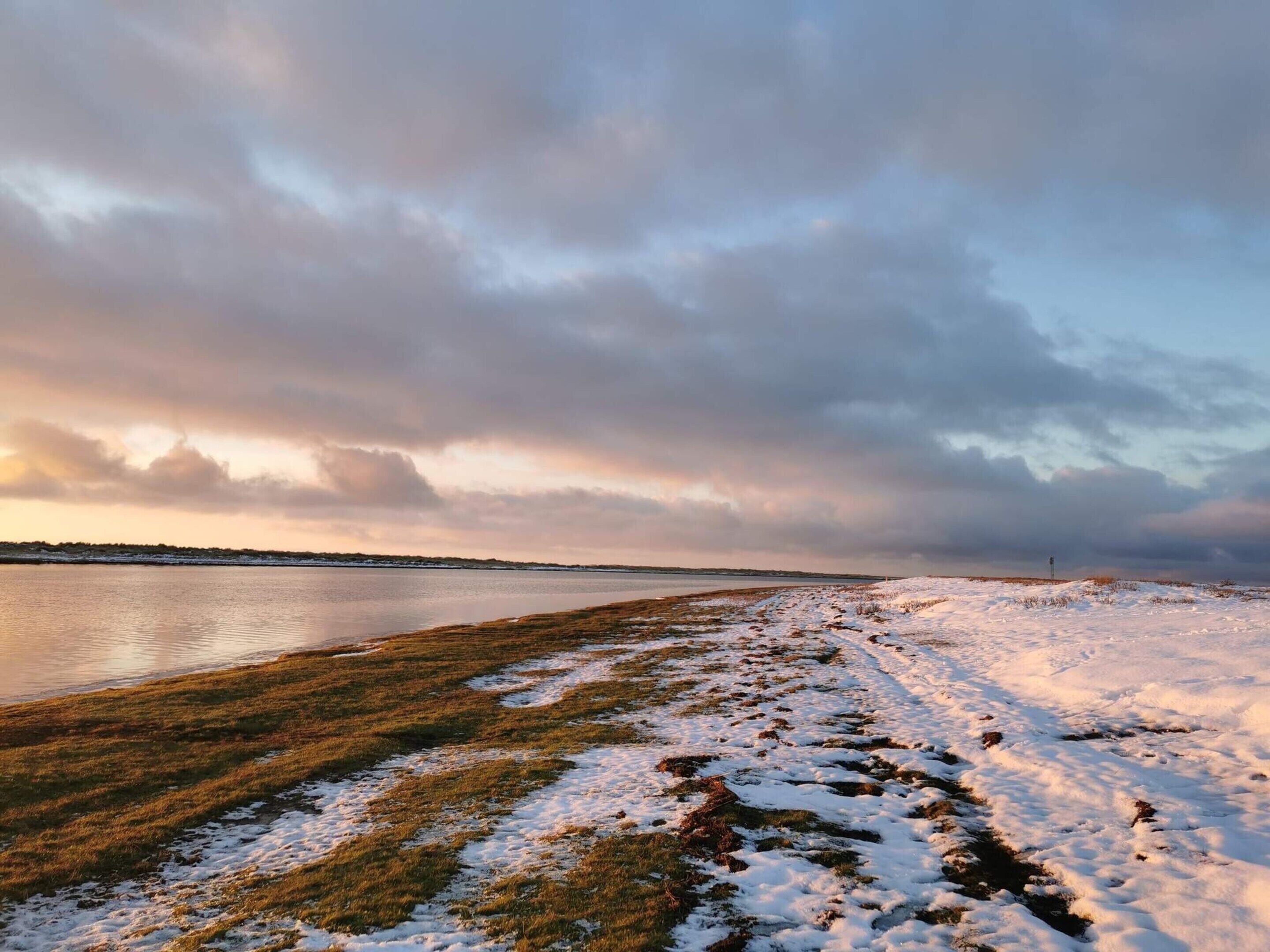 A snowy landscape with a body of water and a distant horizon.