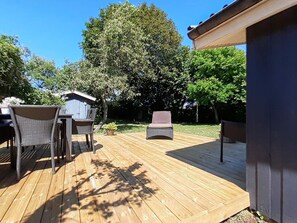 A wooden deck with outdoor furniture, a small shed, and a large tree.
