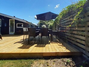 A wooden deck with outdoor furniture, a covered area, and a building with a sliding door.