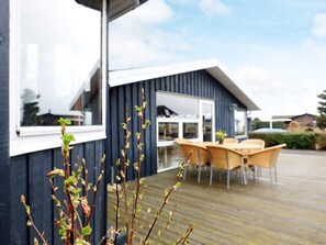 A modern house with a deck, outdoor furniture, and a clear sky.