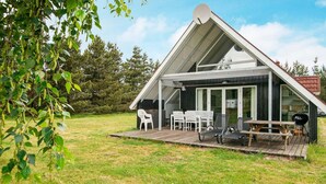 A modern house with a sloped roof, a covered patio with outdoor furniture, and a satellite dish. - 6 Person Holiday Home in Romo (Rømø)