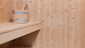 A wooden sauna room with a bench and a wooden bucket with a handle. - Holiday Home in Otterndorf (Otterndorf)