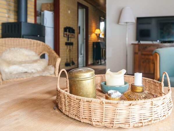 A wicker tray with a jar, candle, and decorative item on a wooden table in a room with a TV and a lamp. - 6 Person Holiday Home in Blokhus (Blokhus)