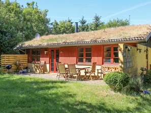 A rustic cabin with a thatched roof, wooden exterior, and a patio area with outdoor seating. - 6 Person Holiday Home in Blokhus (Blokhus)