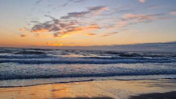 Una playa con olas y un atardecer.
