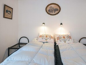 A bed with a white quilt and two pillows with floral embroidery, a framed picture on the wall, and two bedside lamps. - 6 Person Holiday Home in Blokhus (Blokhus)