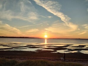 A sunset over a body of water with a person and a dog on the shore. - 5 Star Holiday Home in Hojslev (Hojslev)