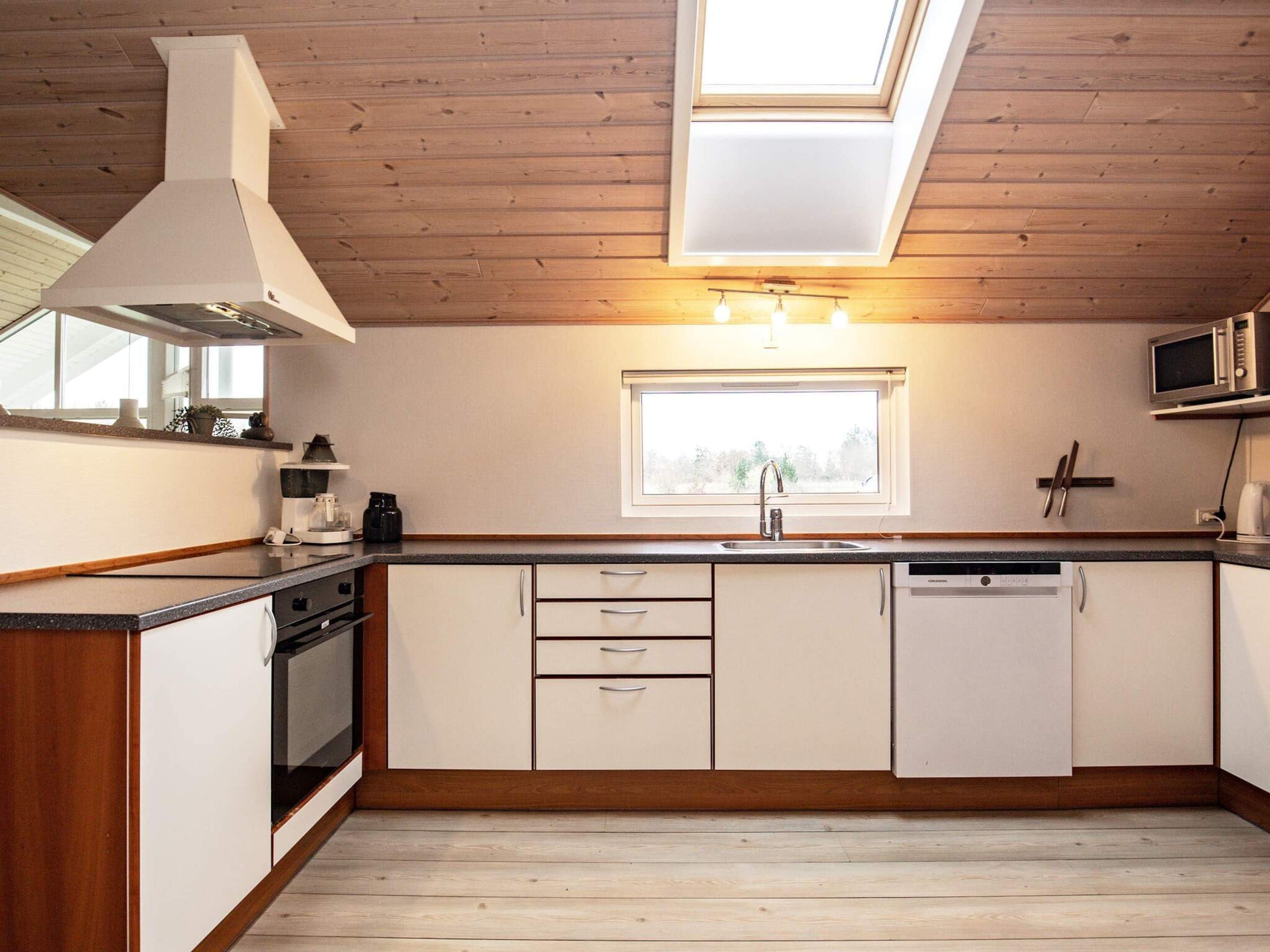 Une cuisine moderne avec un plafond en bois, une lucarne, un four à micro-ondes encastré et un lave-vaisselle.