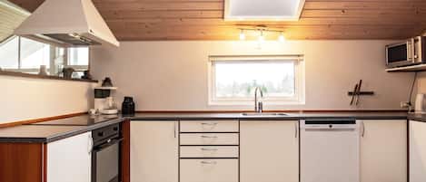 A modern kitchen with wooden ceiling, a skylight, a built-in microwave, and a dishwasher.