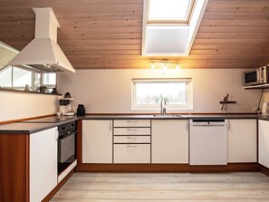 A modern kitchen with wooden ceiling, a skylight, a built-in microwave, and a dishwasher. - 5 Star Holiday Home in Hojslev (Hojslev)