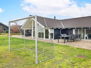 Un quartier résidentiel comprenant une maison, une terrasse avec des meubles d’extérieur et un but de football.