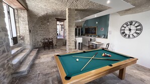 A pool table in a room with stone walls and a kitchen area. - Gîte Léonie "Between Cèze and Ardèche" 30430 BARJAC (Barjac)