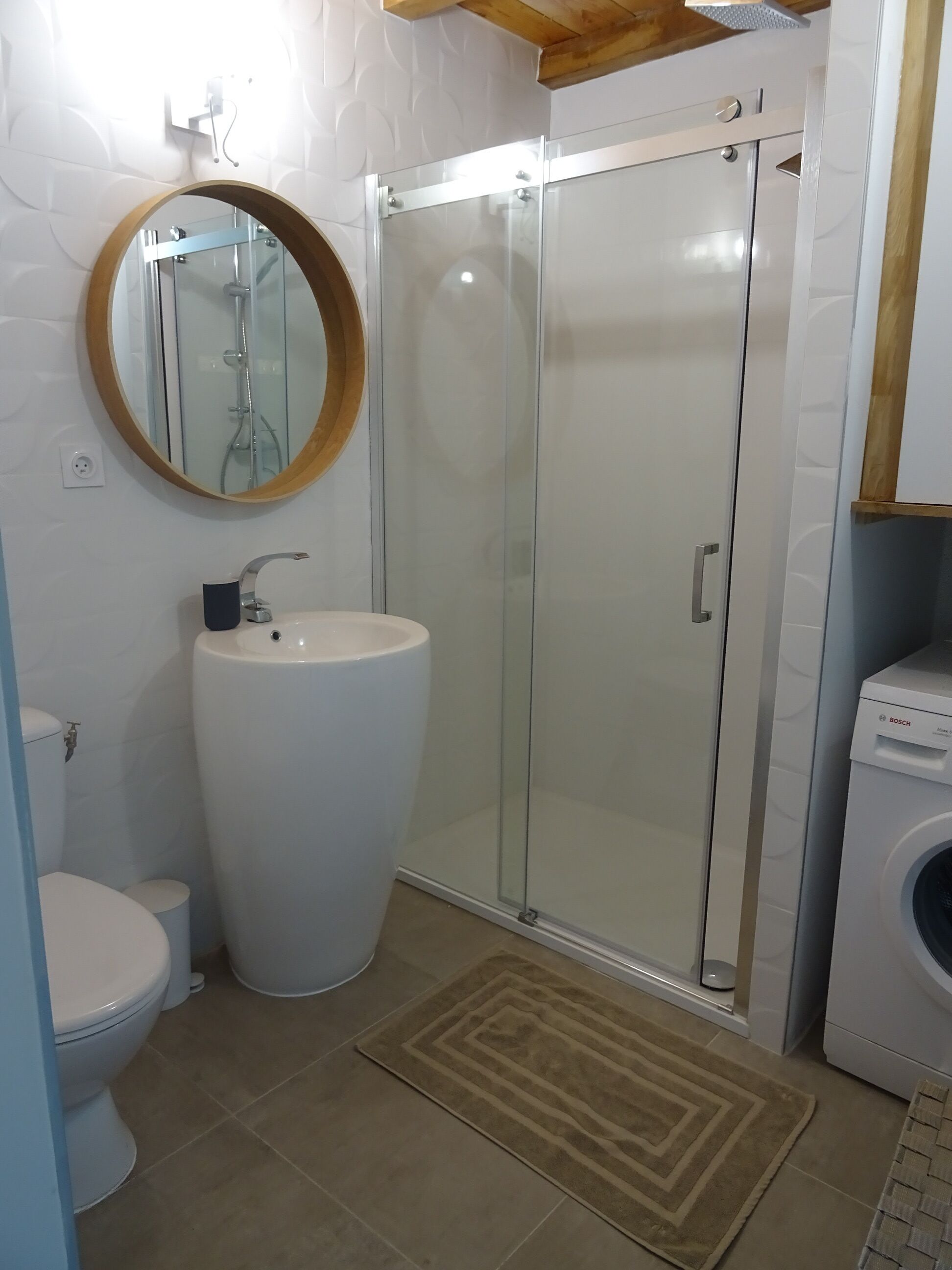 Une salle de bain équipée de toilettes, d’un lavabo, d’une douche et d’un lave-linge.