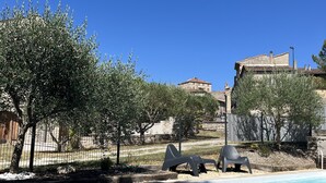 A swimming pool with a clear blue sky, olive trees, and a building in the background. - Gîte Léonie "Between Cèze and Ardèche" 30430 BARJAC (Barjac)