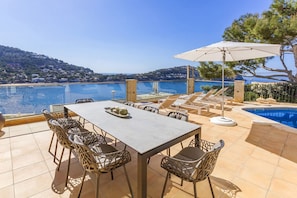 En terrass med pool, matplats och utsikt över havet.
