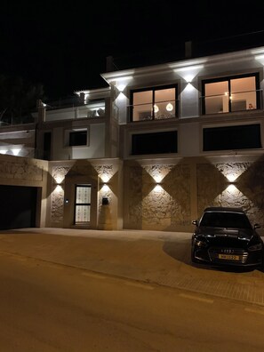 A multi-story house with a garage, a driveway, and a black car parked in the driveway. - Private Detached Villa, sea and port view, several terraces, South facing (Port d'Andratx)