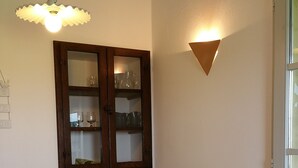 A dining area with a wooden table and four chairs, a cabinet with glass doors, and a wall-mounted light fixture.