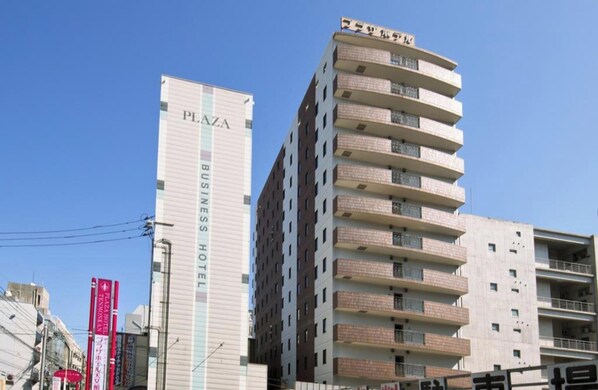 Un hotel de negocios con un llamativo letrero 'PLAZA', varios pisos y un diseño arquitectónico moderno.