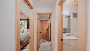 A narrow hallway with wooden doors leading to a bedroom and a bathroom.