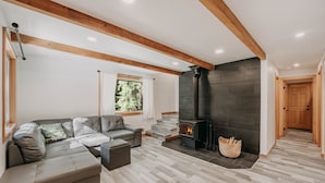 A modern living room with a sectional sofa, a fireplace, and wooden beams on the ceiling.