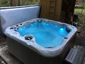 A hot tub with a built-in heater, a ladder, and a wooden structure in the background.