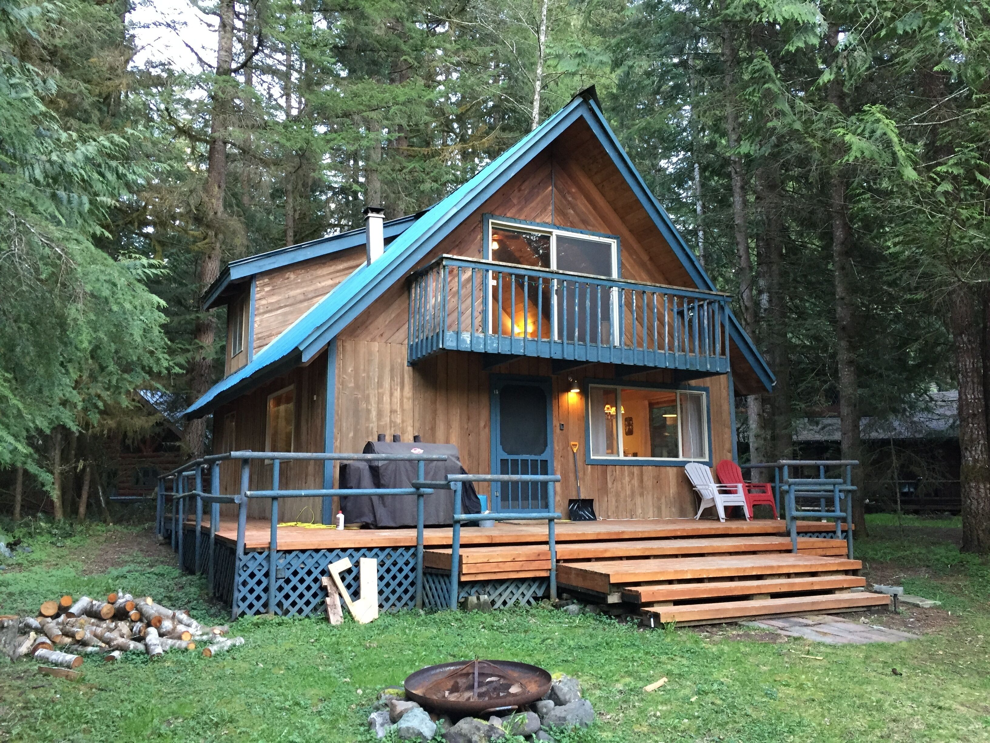 A cabin with a balcony, a deck, and a fire pit.