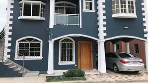 A two-story house with a garage, a staircase, and a car parked in the driveway. - My Second Home In Puerto Plata (Puerto Plata)