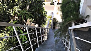 Un escalier avec des rampes en métal, entouré de verdure.
