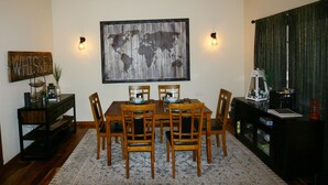 Uma sala de jantar com uma mesa e cadeiras de madeira, uma obra de arte com um mapa mundi e um letreiro com a palavra 'WHISKEY'.