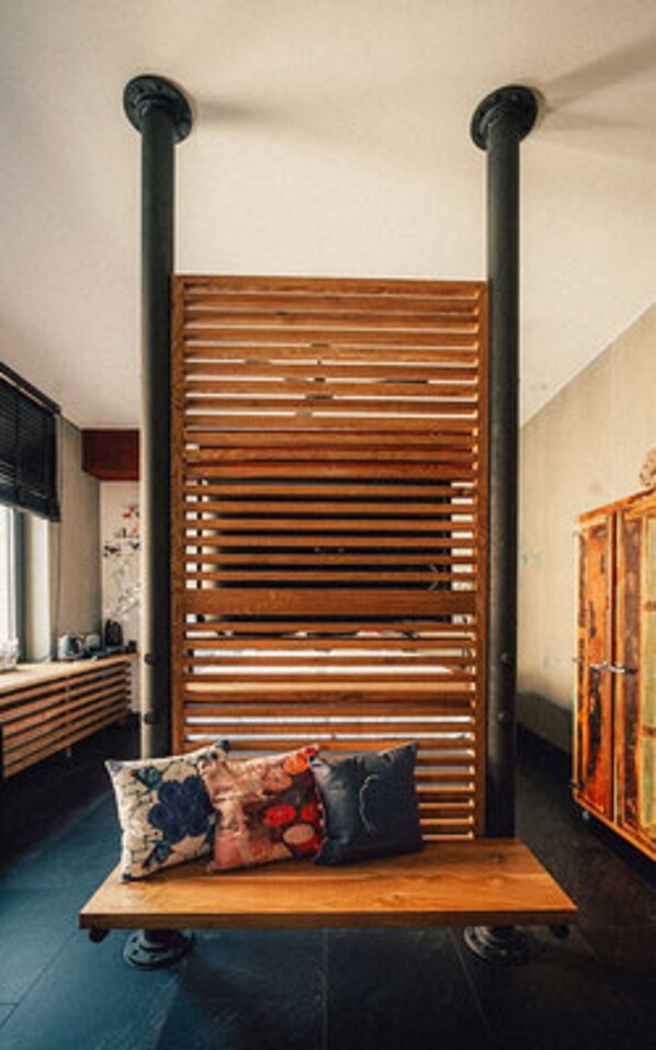 A room with a wooden slatted partition, a wooden bench with cushions, and a cabinet. - 36 Phô Cô Hotel & Suites (Weimar)