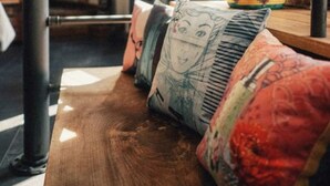 A wooden bench with colorful cushions in a room with brick walls and large windows. - 36 Phô Cô Hotel & Suites (Weimar)